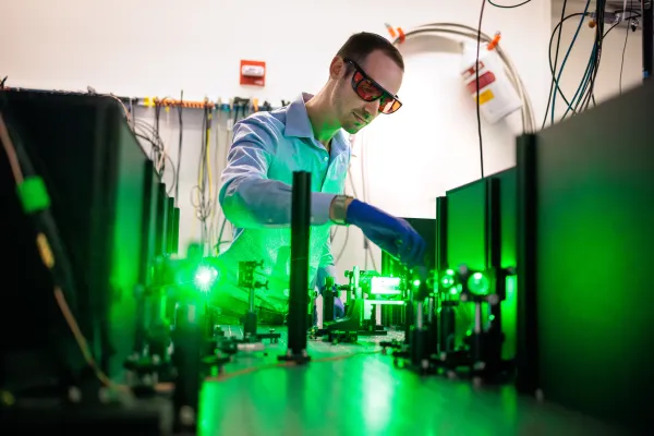 Male in lab wearing protective eye wear and gloves.